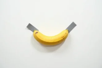 Banane mûre scotchée sur un mur blanc de galerie d'art contemporain, œuvre virale inspirée de l'art conceptuel